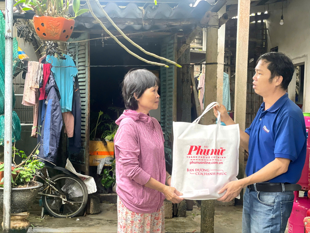 Phóng viên Thuận Hóa (Báo Phụ nữ TPHCM) trao quà của bạn đọc hỗ trợ bà Lê Thị Cúc (ngụ xã Quảng Điền, TP Huế) - ẢNH: NGỌC MINH
