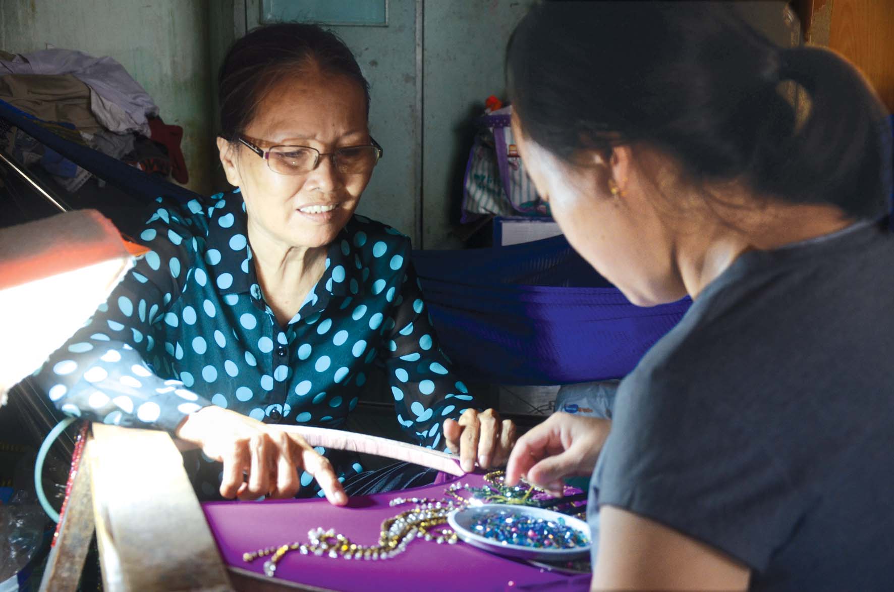 Nạn nhân nữ bị bạo hành (bìa phải) được chị Bích Thủy hướng dẫn nghề kết cườm trong thời gian tạm lánh tại địa chỉ  tin cậy cộng đồng