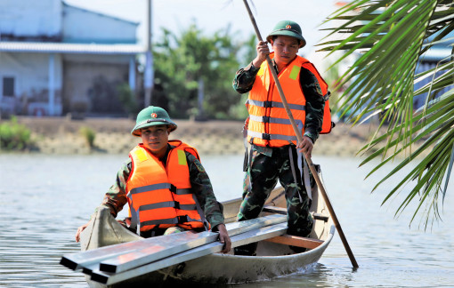 Bộ đội dùng ghe, thuyền vận chuyển vật liệu qua sông, xây mái ấm cho đồng bào sau lũ